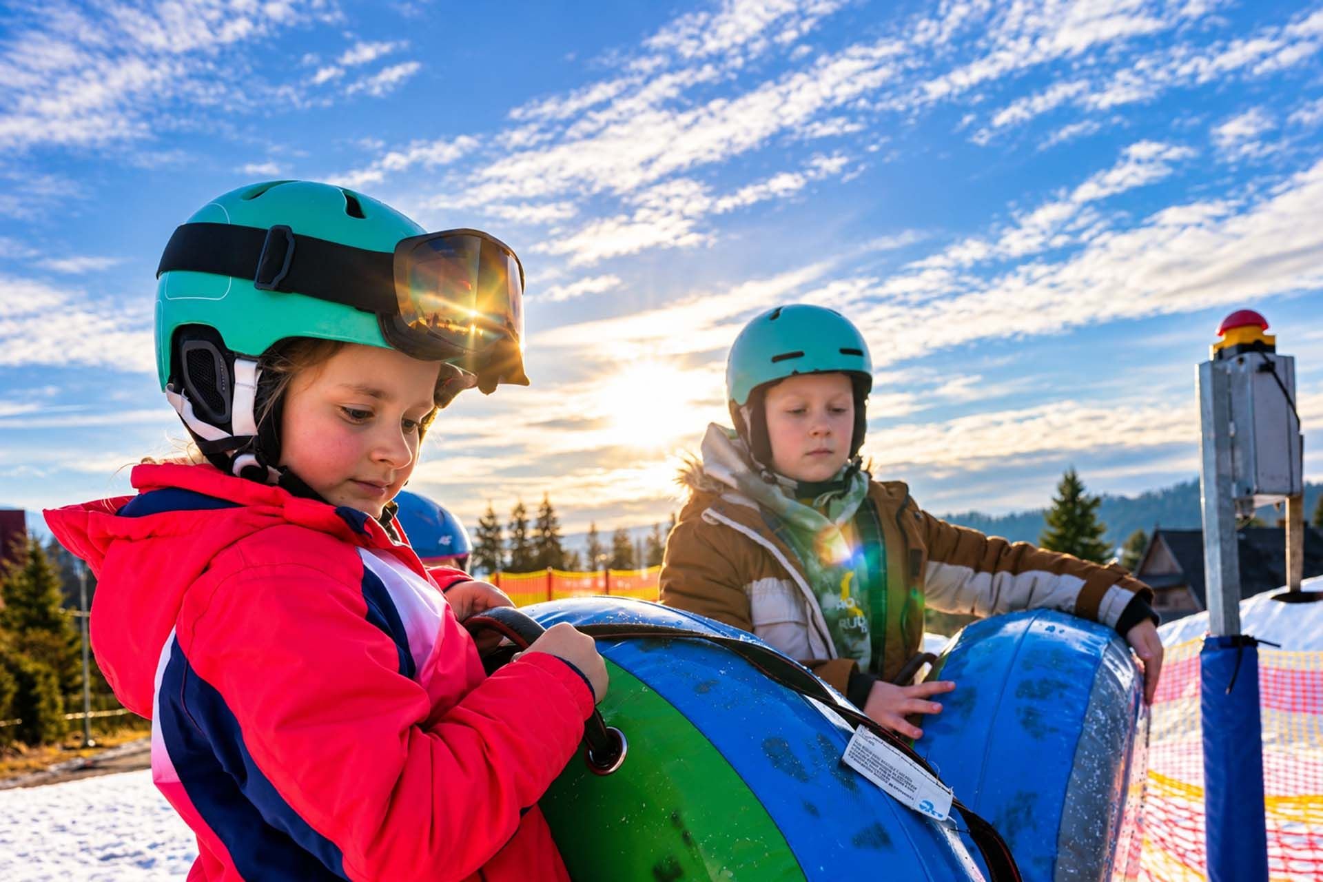 Dzieci na Snow Camp  z dmuchanymi kółkami na snowtubing czekające na zjazd w tle piękny wschód słońca,