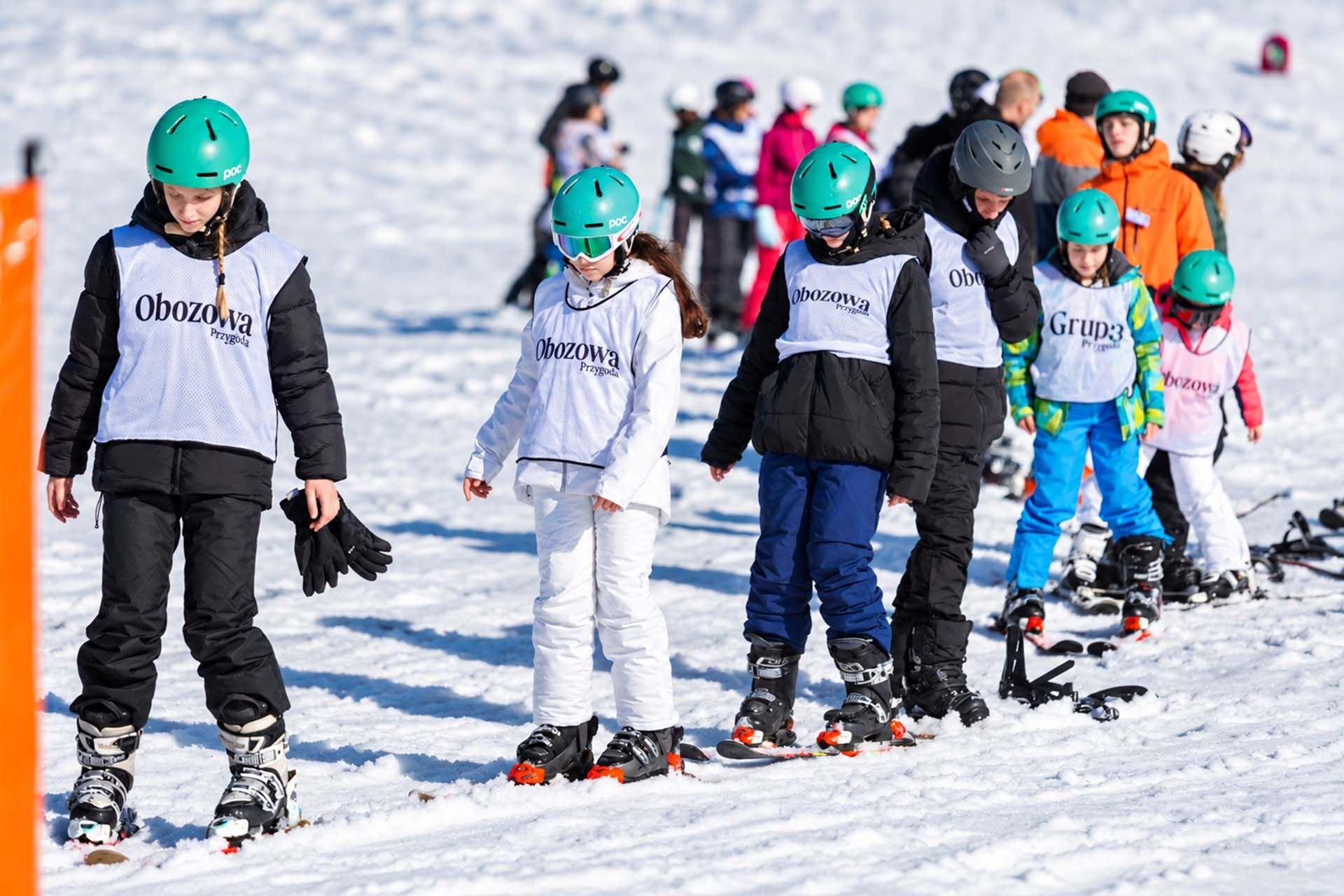 Dzieci na stoku narcairskim jadące w rządku ski camp