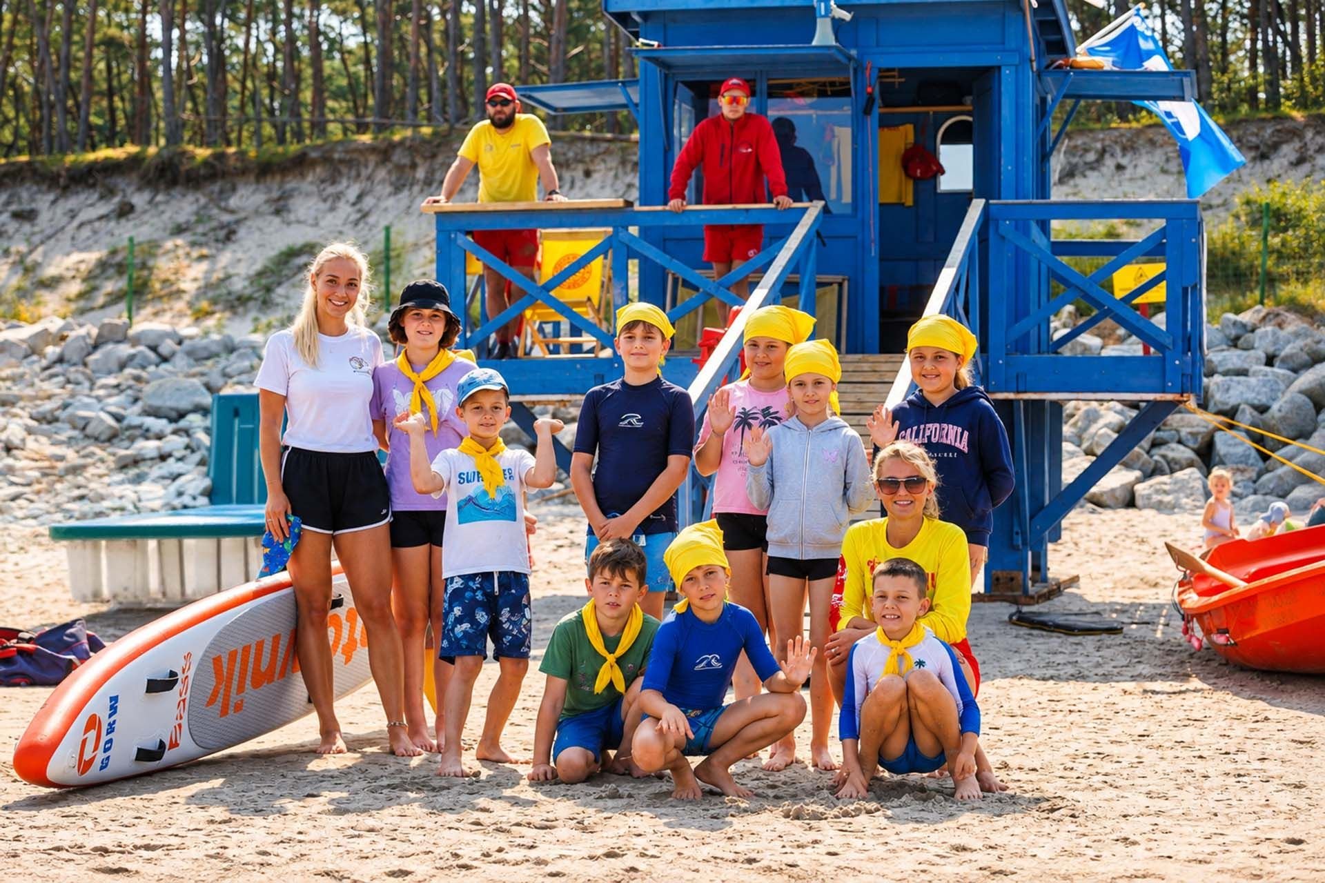 Letnia ekipa obozowiczów na plaży w Pogorzelicy z instruktorką i ratownikiem