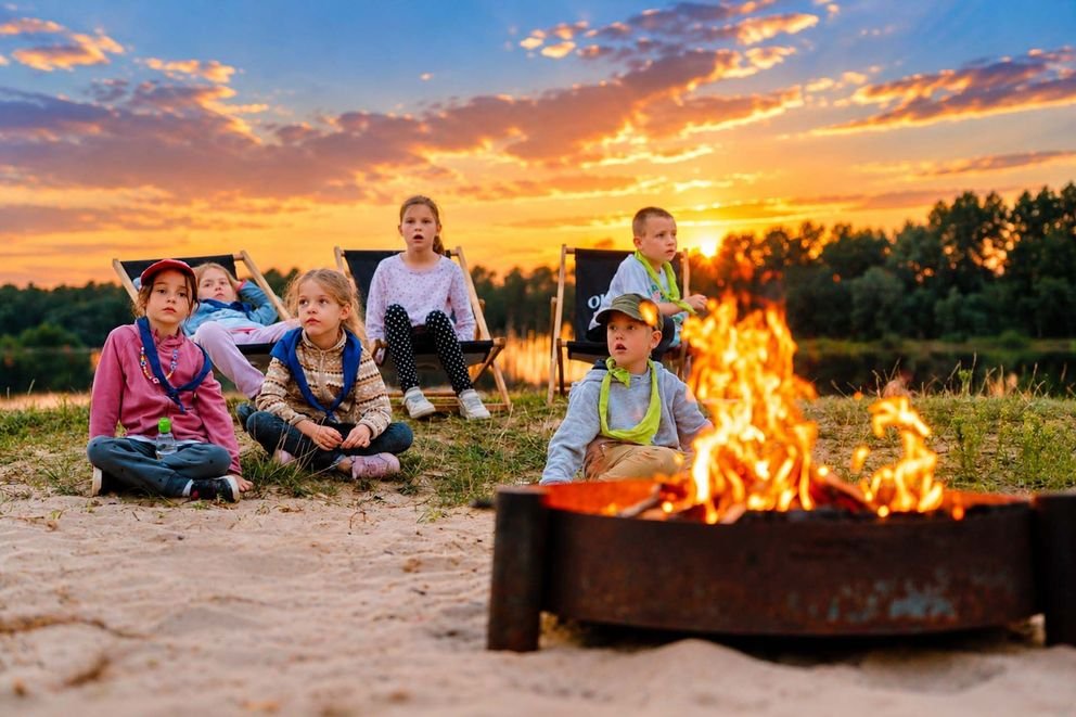 Kids Camp w Smerzynie, dzieci przy ognisku na plaży w tle widać zachód słonca oraz lasy w oddali
