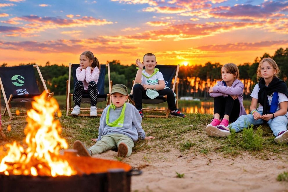 Kids Camp w smerzynie, dzieci przy ognisku uśmiechnięte chłopiec macha