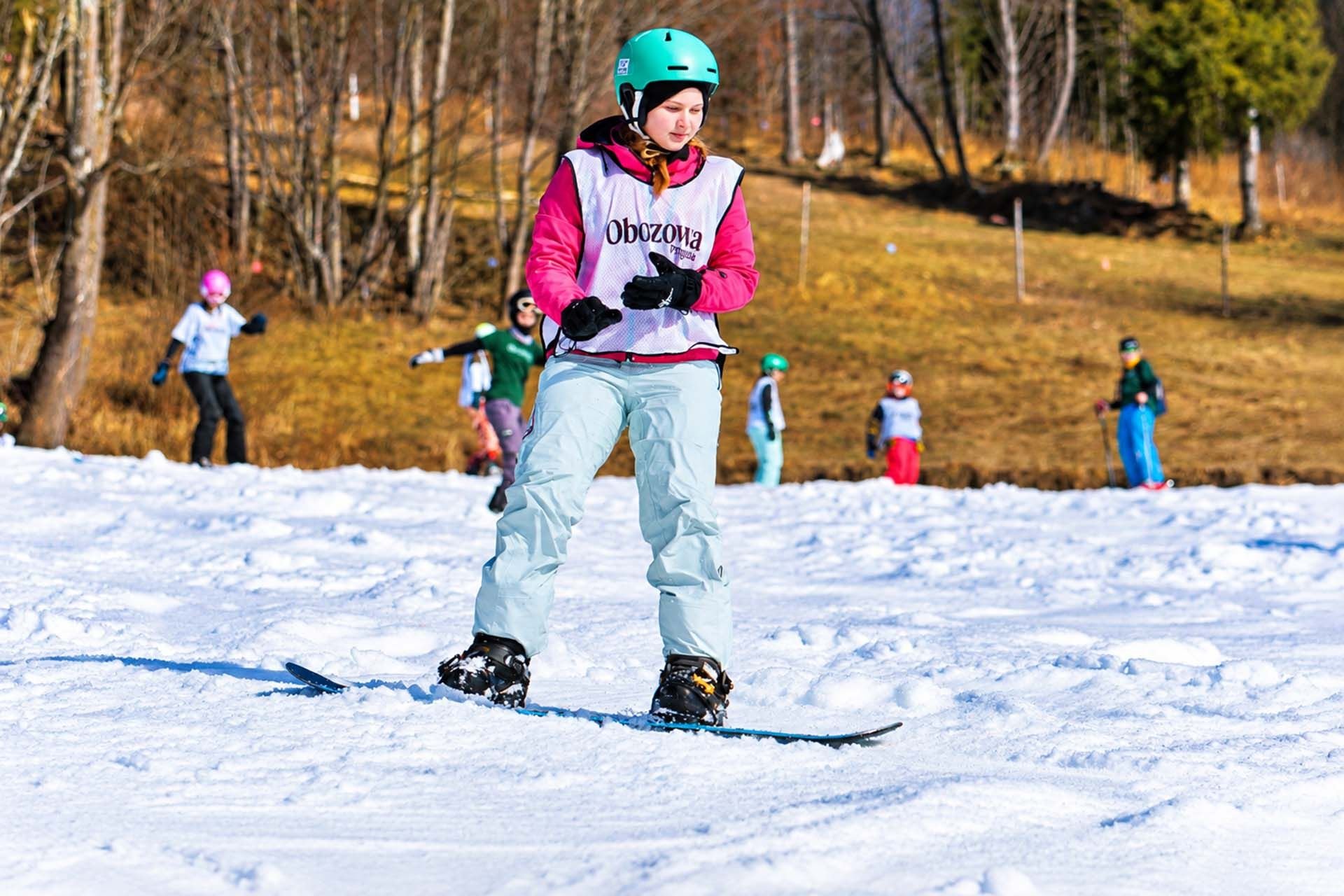 Dziewczynka jeździ na snowboardzie - pomysły na ferie zimowe dla dzieci