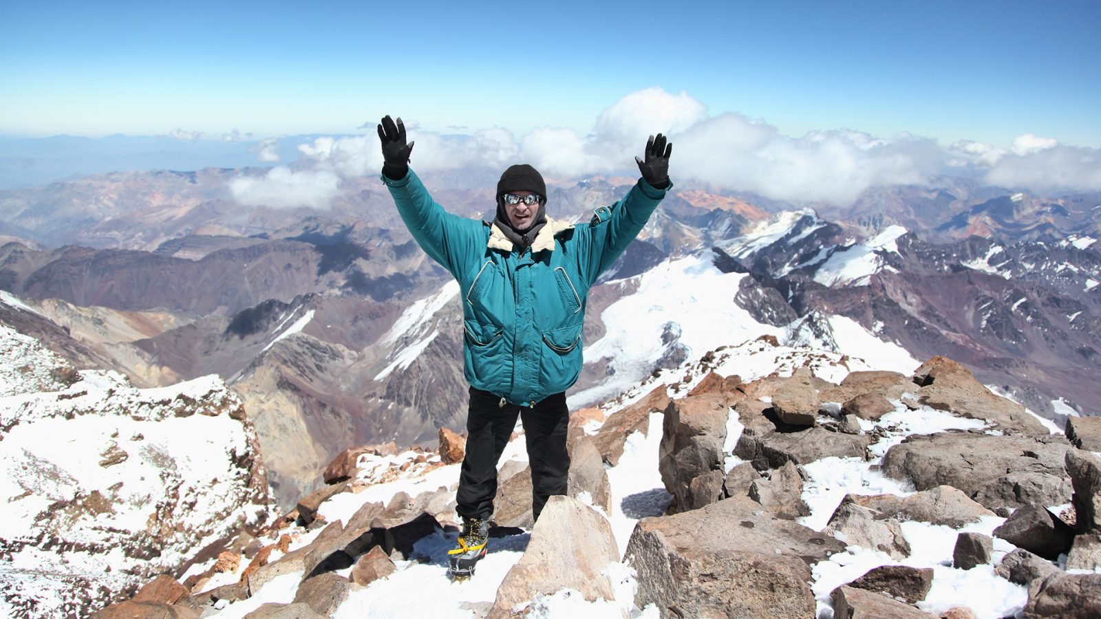 Wspinacz na szczycie Aconcagui z uniesionymi rękami.