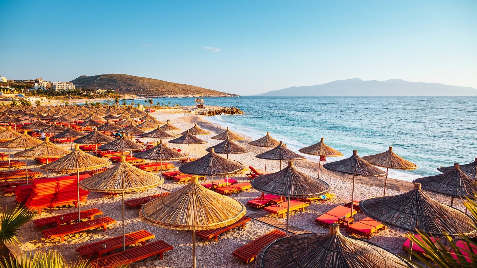 plaża z kolorowymi parasolami ułożonymi w rzędzie na miękkim piasku. Lokalizacja: Saranda, albański kurort