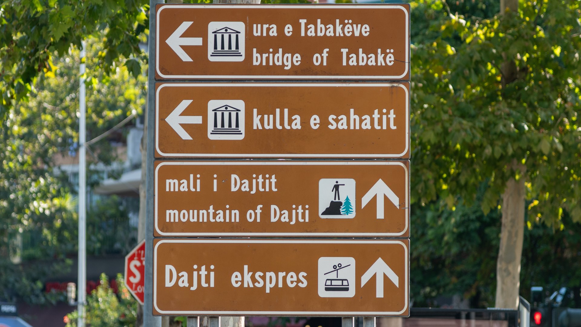 Brązowe znaki kierunkowskazów po albańsku w centrum Tirany