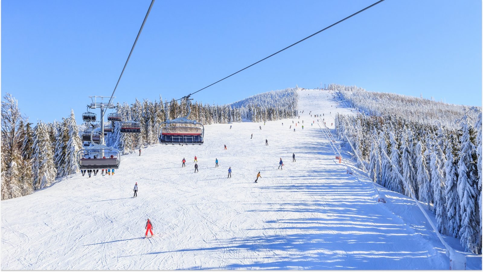 Zaśnieżony stok narciarski z wyciągiem krzesełkowym
