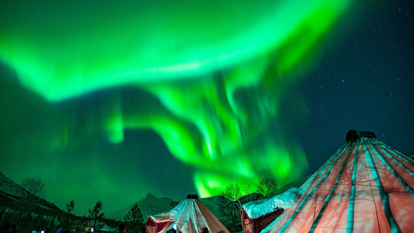 Zorza widoczna nad domkami rdzennej ludności północy - Sámi