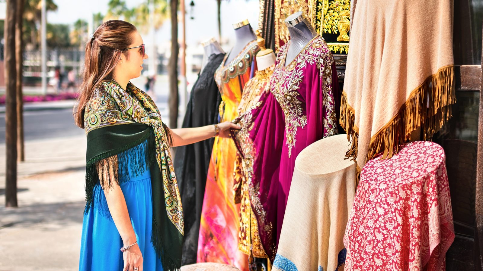 Kobieta na suku. Turysta ogląda tradycyjne arabskie stroje i ubrania na targu