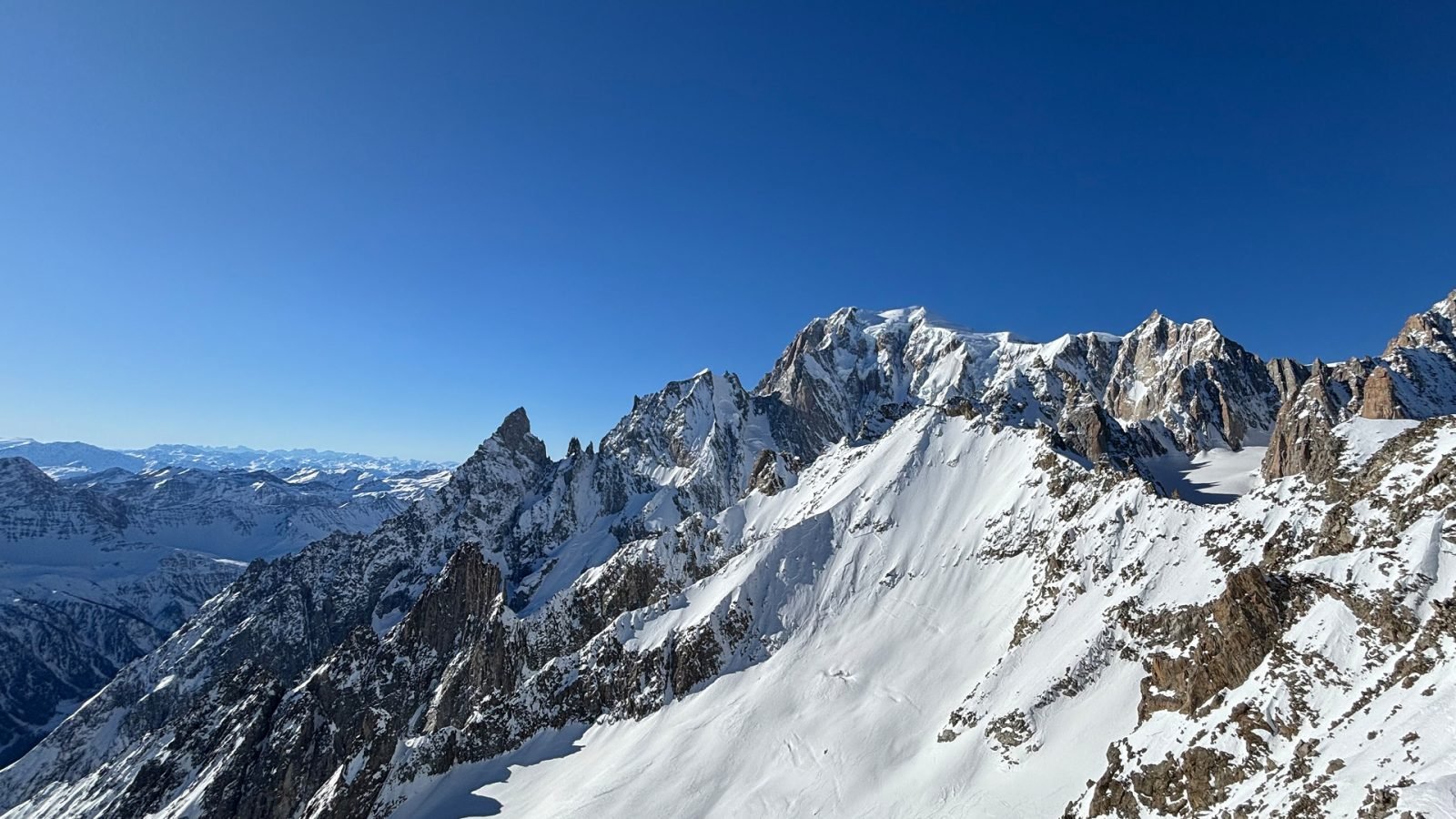 Zapierający dech w piersiach widok na ośnieżony masyw Mont Blanc pod czystym, błękitnym niebem, oferujący wspaniałą panoramę włoskich Alp w Courmayeur