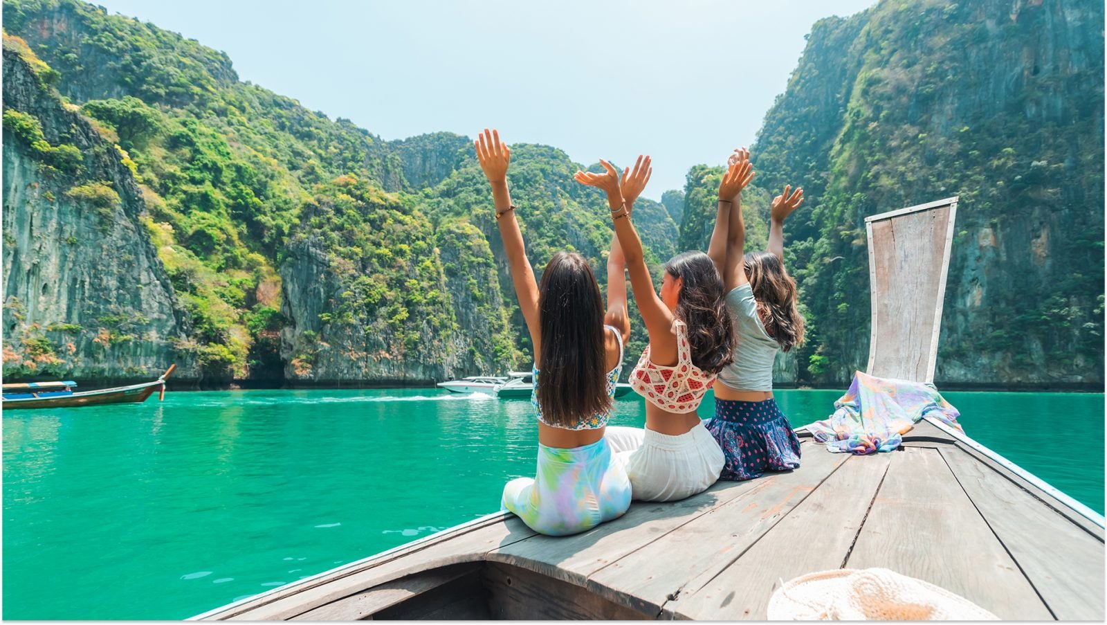 Szczęśliwe przyjaciółki siedzące na drewnianej łodzi, wyglądając na piękną przyrodę tropikalnej wyspy w Krabi, Tajlandia