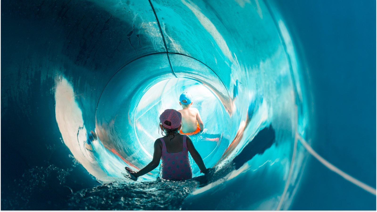 Chłopiec i dziewczynka zjeżdżają ze zjeżdżalni wodnej.