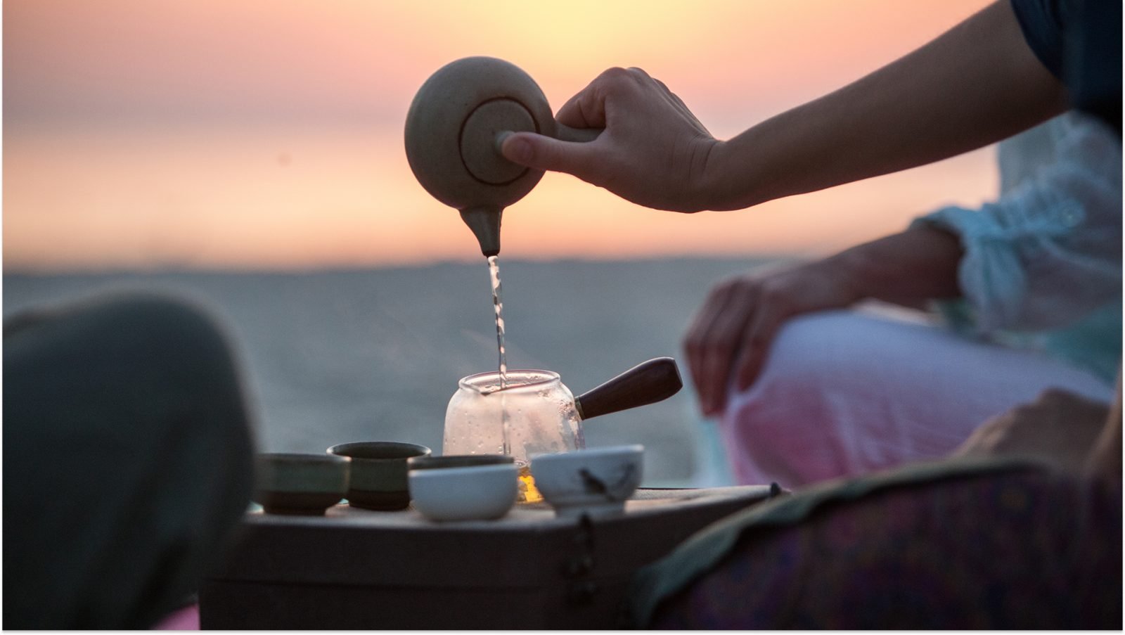 Ludzie parzący herbatę metodą gongfu cha o zachodzie słońca