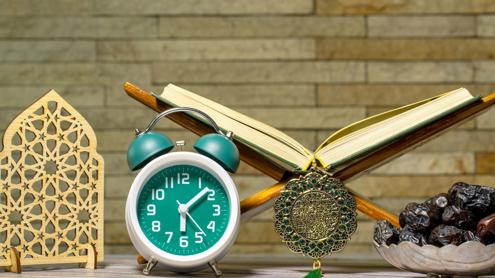 Tło Ramadan Kareem przedstawiające eleganckie złote dekoracje, owoce daktyli, zegar biurkowy przedstawiający czas pierworodny i Święty Koran - symbolizujący wiarę, tradycję i duchową istotę Ramadanu