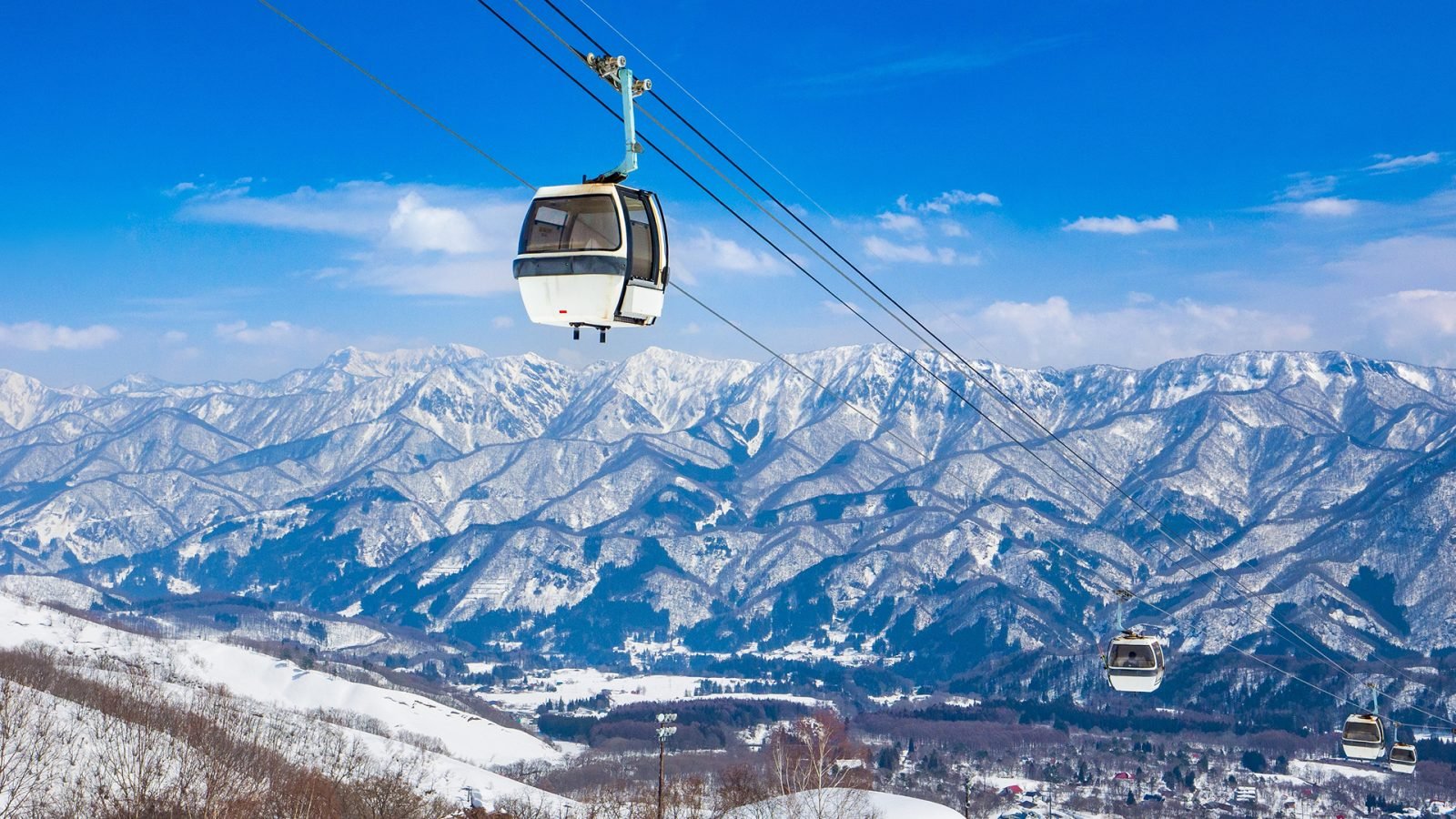 Kolejka gondolowa wjeżdżająca na stoki narciarskie z panoramicznym widokiem na ośnieżoną dolinę (Tsugaike Kogen, Hakuba, Nagano, Japonia)