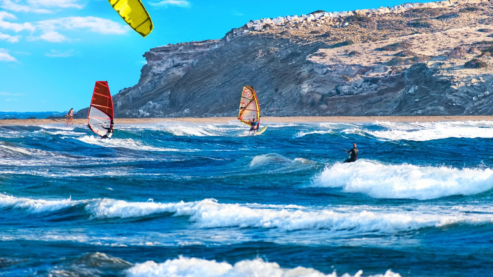 Dwóch windsurferów i kitesurfer na plaży Prasonisi (Rodos, Grecja)
