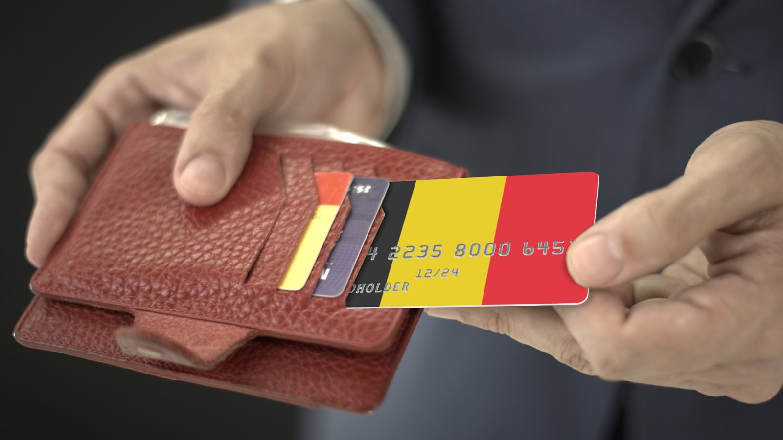 Biznesmen wyciąga z portfela kartę kredytową z flagą Belgii.