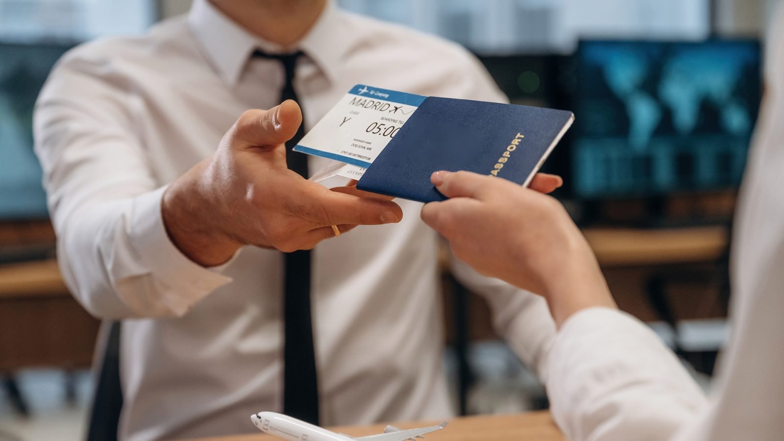 Kobieta wręcza kartę pokładową i bilety pracownikowi linii lotniczych.