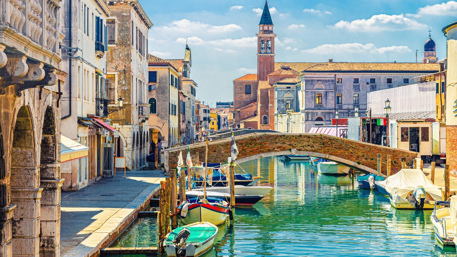 Pejzaż miejski w Chioggii z wąskim kanałem wodnym z zacumowanymi wielokolorowymi łodziami, Wenecja