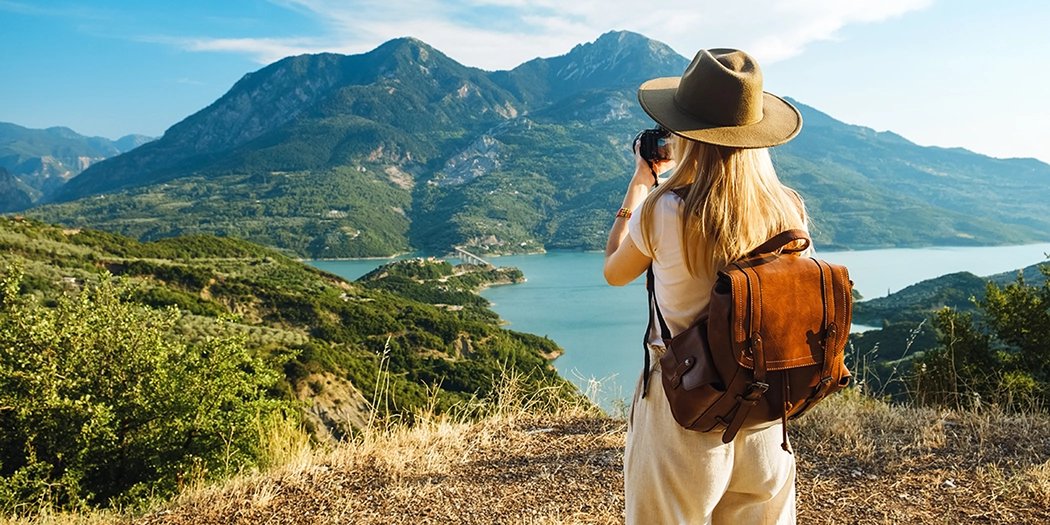 Kobieta podczas wycieczki dla singli fotografuje górski krajobraz nad jeziorem
