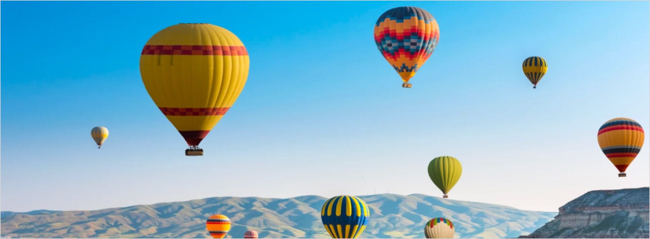 Kolorowe balony na gorące powietrze nad malowniczą doliną